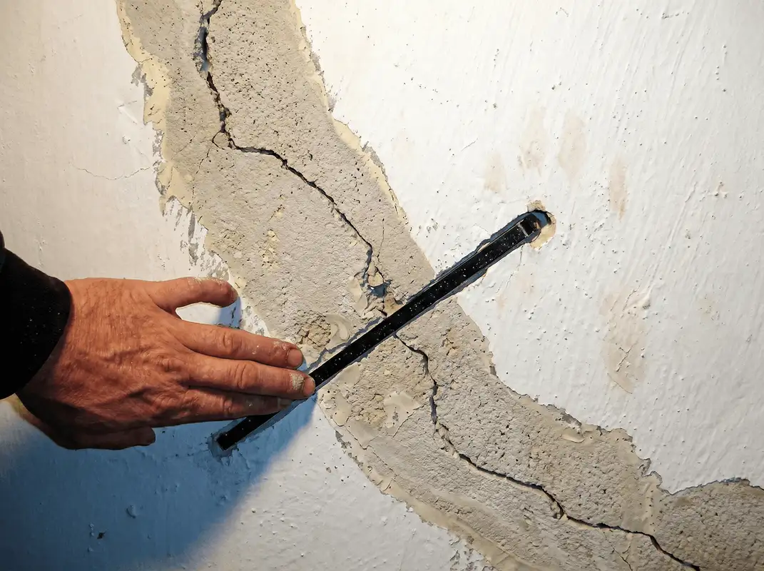 A wall with a large crack is being inspected by a professional in Worcester, MA