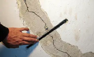 A wall with a large crack is being inspected by a professional in Worcester, MA